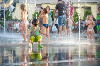 Kiev, Ukrayna 13 Ağustos 2017: Happy kids sıcak yaz gününde şehir su fıskiyede oynamak eğlenceli. Ebeveynler çocuklarıyla birlikte. Etkin aile boş, ekoloji kavramı.