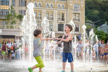 Kiev, Ukrayna 13 Ağustos 2017: Happy kids sıcak yaz gününde şehir su fıskiyede oynamak eğlenceli. Ebeveynler çocuklarıyla birlikte. Etkin aile boş, ekoloji kavramı.