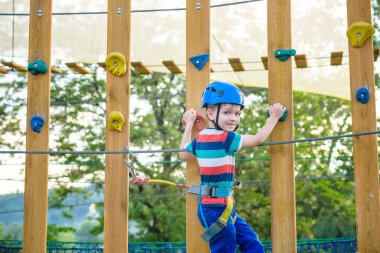 Çocuk Macera Parkı'nda eğleniyor. bir ip Bahçesi yapısında tırmanma yürümeye başlayan çocuk. bir ip Bahçesi yapısında tırmanma yürümeye başlayan çocuk. Kask ve kemer ile güvenli tırmanma aşırı spor