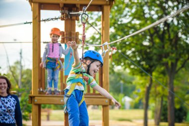 Sevimli küçük çocuk macera parkı, annesi onu aile hafta sonu etkinlikleri, bir yardım eli veren bir ip Bahçesi yapı zamanında tadını açık bahar