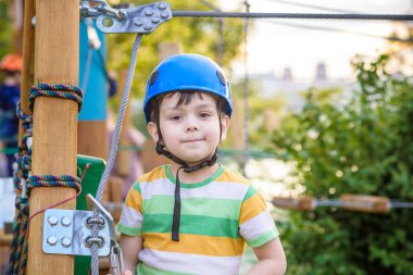 Küçük şirin çocuk aktivite bir tırmanma macera parkta yaz güneşli bir günde zevk. bir ip Bahçesi yapısında tırmanma yürümeye başlayan çocuk. Kask ve kemer ile güvenli tırmanma aşırı spor. sigorta
