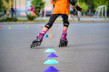 KYIV, UKRAINE JUNE 26, 2018: Attractive teenage girl roller skating on roller blades on a tarred rural road rounding a bend at speed with her arms flying clipart