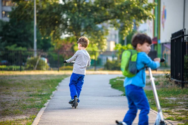 Two Cute Boys Compete Riding Scooters Outdoor Park Summertime Kids — Stock Photo, Image