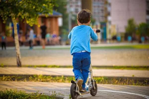 At Binme küçük yürümeye başlayan çocuk ve onun scooter yaz sıcak akşam Park.