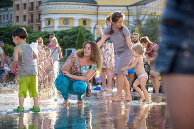 Kiev, Ukrayna 13 Ağustos 2017: Happy kids sıcak yaz gününde şehir su fıskiyede oynamak eğlenceli. Ebeveynler çocuklarıyla birlikte. Etkin aile boş, ekoloji kavramı.