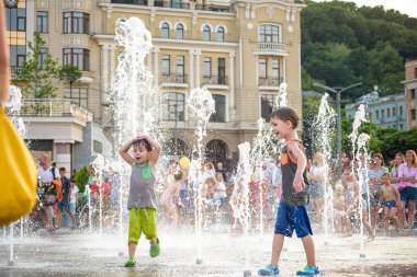 Kiev, Ukrayna 13 Ağustos 2017: Happy kids sıcak yaz gününde şehir su fıskiyede oynamak eğlenceli. Ebeveynler çocuklarıyla birlikte. Etkin aile boş, ekoloji kavramı.