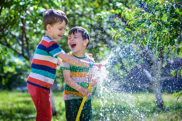 Hortum bahçede sulama ile sulama tesisleri şirin ufaklık. Ebeveynler ağaçlar büyümeye yardımcı ve eğlenmek çok güzel küçük bir çocuk. Çocuklar açık havada etkinliklerle.