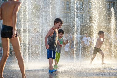Kiev, Ukrayna 13 Ağustos 2017: Happy kids sıcak yaz gününde şehir su fıskiyede oynamak eğlenceli. Ebeveynler çocuklarıyla birlikte. Etkin aile boş, ekoloji kavramı.