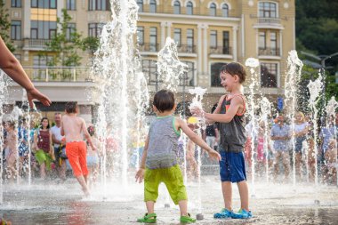Kiev, Ukrayna 13 Ağustos 2017: Happy kids sıcak yaz gününde şehir su fıskiyede oynamak eğlenceli. Ebeveynler çocuklarıyla birlikte. Etkin aile boş, ekoloji kavramı.