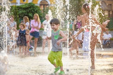 Kiev, Ukrayna 13 Ağustos 2017: Happy kids sıcak yaz gününde şehir su fıskiyede oynamak eğlenceli. Ebeveynler çocuklarıyla birlikte. Etkin aile boş, ekoloji kavramı.