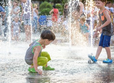 Heyecanlı çocuk su jetleri, Çeşme arasında eğleniyor. Şehirde yaz. Çocuk mutlu gülümseme yüzünü. Ekoloji kavramı.
