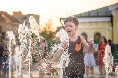 Heyecanlı çocuk su jetleri, Çeşme arasında eğleniyor. Şehirde yaz. Su ile el mutlu gülümseme yüz den vurdum. Ekoloji kavramı.
