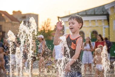 Heyecanlı çocuk su jetleri, Çeşme arasında eğleniyor. Şehirde yaz. Su ile el mutlu gülümseme yüz den vurdum. Ekoloji kavramı.