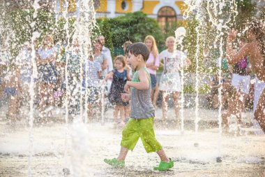 Heyecanlı çocuk su jetleri, Çeşme arasında eğleniyor. Şehirde yaz. Çocuk mutlu gülümseme yüzünü. Ekoloji kavramı.