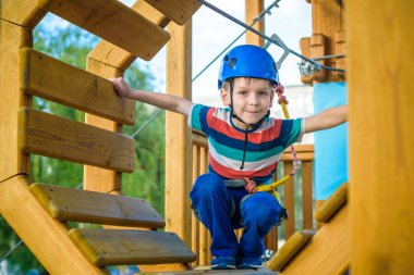 Eğleniyor ve Macera Parkı'nda oynarken, ipleri tutan ve Ahşap merdiven çıkma mutlu çocuk.