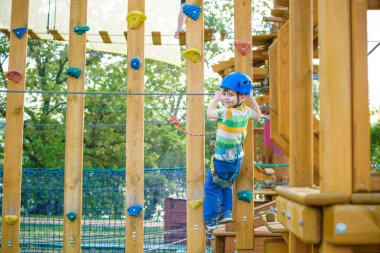 Macera Parkı'nda eğleniyor ve miğfer kameraya gülümseyen cesur küçük çocuk. bir ip Bahçesi yapısında tırmanma yürümeye başlayan çocuk. İzci rappelling pratik