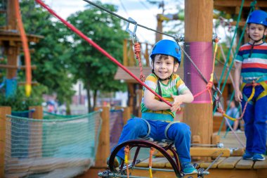 Küçük şirin çocuk aktivite bir tırmanma macera parkta yaz güneşli bir günde zevk. bir ip Bahçesi yapısında tırmanma yürümeye başlayan çocuk. Kask ve kemer ile güvenli tırmanma aşırı spor. sigorta