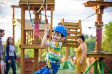 Küçük şirin çocuk aktivite bir tırmanma macera parkta yaz güneşli bir günde zevk. bir ip Bahçesi yapısında tırmanma yürümeye başlayan çocuk. Kask ve kemer ile güvenli tırmanma aşırı spor. sigorta