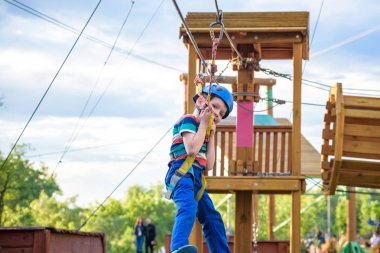 Küçük şirin çocuk aktivite bir tırmanma macera parkta yaz güneşli bir günde zevk. bir ip Bahçesi yapısında tırmanma yürümeye başlayan çocuk. Kask ve kemer ile güvenli tırmanma aşırı spor. sigorta