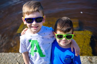 Şehir nehir ya da göl kıyısında parlak güneşli bir günde mutlu çocuk portresi. Dostluk. Yaz tatili.