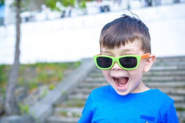 Korkmuş şaşırmış şaşkın karışık beyaz erkek çocuk güneş gözlüklü, tuğla beyaz duvar arka planı teşkil etmektedir. Beyaz çocuk modelleri açık havada heyecanlı.