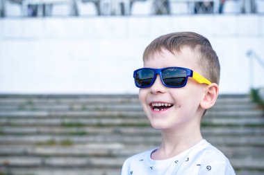 Korkmuş şaşırmış şaşkın karışık beyaz erkek çocuk güneş gözlüklü, tuğla beyaz duvar arka planı teşkil etmektedir. Beyaz çocuk modelleri açık havada heyecanlı.