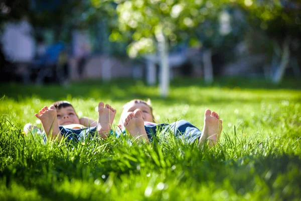 Çim döşeme çocuk. Bahar park aile pikniği. Çim üzerinde yalan ve dinlenme birkaç bacaklar görüntüsü. Gevşeme mutlu çocukluk dostluk kavramı.