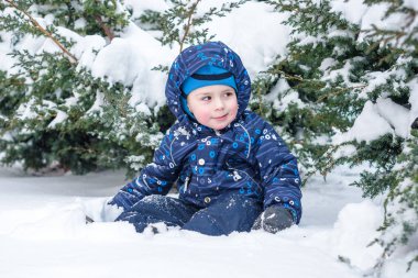 Çocuk çocuk açık havada kar yağışı sırasında renkli giysiler içinde kış portresi. Etkin açık havada eğlence kış soğuk karlı günlerde çocuklu. Mutlu çocuk kar ile eğleniyor