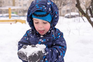 Çocuk kar renkli giysiler açık havada oynarken elinde tutar. Kışın soğuk karlı günlerde çocuklu etkin boş. Evlat gidiş darbe veya olmaması onun dil ile.