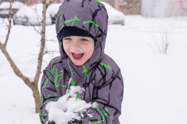 Çocuk kar renkli giysiler açık havada oynarken elinde tutar. Kışın soğuk karlı günlerde çocuklu etkin boş. Evlat gidiş darbe veya olmaması onun dil ile.