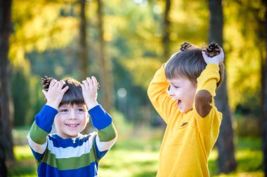 Dışarıda iki büyük kozalakla oynayan iki küçük şirin kardeş. Doğadaki çocuklar için bir oyun. Kardeş kardeşler en iyi arkadaşlardır. Çocuklarla dışarıda arkadaşça vakit geçirmek..