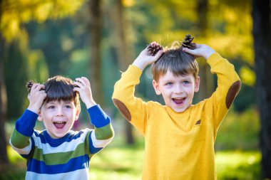 Dışarıda iki büyük kozalakla oynayan iki küçük şirin kardeş. Doğadaki çocuklar için bir oyun. Kardeş kardeşler en iyi arkadaşlardır. Çocuklarla dışarıda arkadaşça vakit geçirmek..