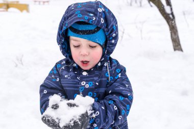 Çocuk kar renkli giysiler açık havada oynarken elinde tutar. Kışın soğuk karlı günlerde çocuklu etkin boş. Evlat gidiş darbe veya olmaması onun dil ile.