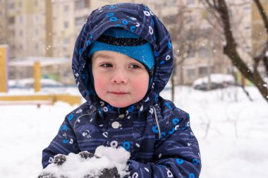Çocuk kar renkli giysiler açık havada oynarken elinde tutar. Kışın soğuk karlı günlerde çocuklu etkin boş. Evlat gidiş darbe veya olmaması onun dil ile.