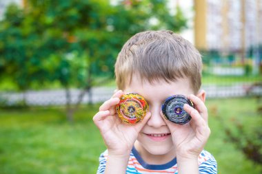 Açık havada modern spin top ile oynayan çocuk. Çocuklar için oyun eğlence. Üst, tetikleyici tarafından tetiklenen. Çocuk göstermek hangi daha iyi olduğunu seçerek iki farklı varyantları.