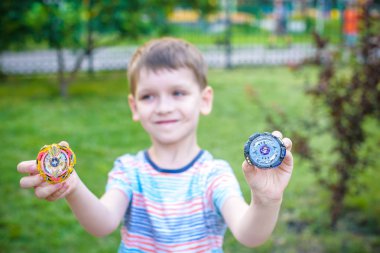 Açık havada modern spin top ile oynayan çocuk. Çocuklar için oyun eğlence. Üst, tetikleyici tarafından tetiklenen. Çocuk göstermek hangi daha iyi olduğunu seçerek iki farklı varyantları.