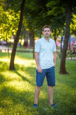 Açık mavi tişörtlü yaz doğa park arka plan dişlere sahip gülümseyen güzel neşeli İspanyol adam portresi kapatın. Moda modeli.
