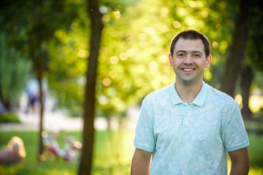 Açık mavi tişörtlü yaz doğa park arka plan dişlere sahip gülümseyen güzel neşeli İspanyol adam portresi kapatın. Moda modeli.