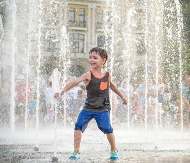Heyecanlı çocuk su jetleri, Çeşme arasında eğleniyor. Şehirde yaz. Su ile el mutlu gülümseme yüz den vurdum. Ekoloji kavramı.
