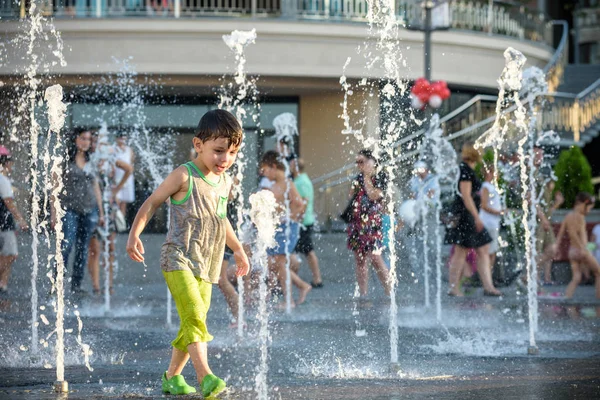 兴奋的男孩在水射流之间的乐趣 在喷泉 夏天在城市 孩子快乐的笑脸 生态学概念 — 图库照片