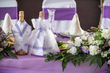 Düğün. Ziyafet. Konuklar, yuvarlak masa ve sandalyeler çatal bıçak takımı, çiçekler ve çanak çömlek ile servis ve bir masa örtüsü ile kaplı.