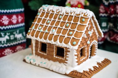 Ev yapımı Noel Gingerbread ev içinde belgili tanımlık kar. Arka planda bir şekilde dekore edilmiş Noel ağacı.