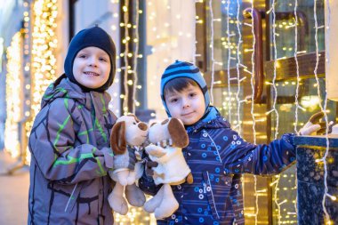 Aile, çocukluk, sezon ve insanlar kavramı - mutlu çocuklar kardeşler çocuklar kış giysileri xmas lights bokeh ile kar şehir arka plan üzerinde kukla ile oynamak