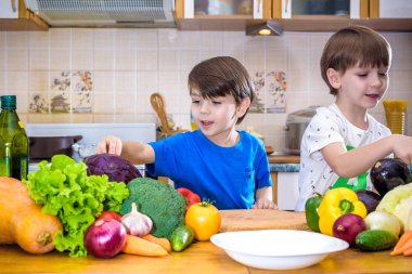 Sağlıklı beslenme. Mutlu çocuk hazırlar ve mutfakta sebze salatası yiyor. Sağlık ve dostluk kavramı.