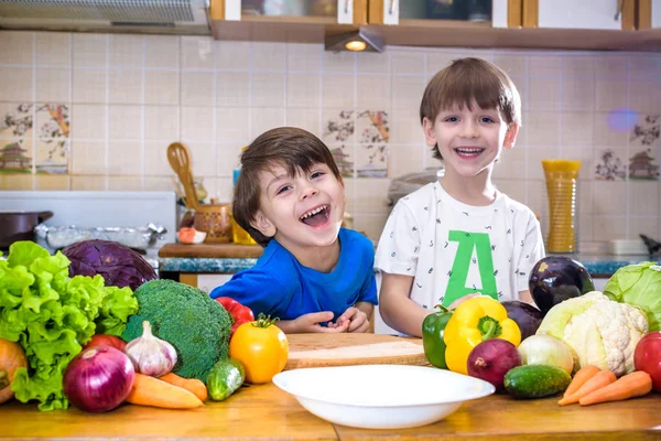 Healthy eating. Happy children prepares and eats vegetable salad in kitchen. Health and friendship concept.