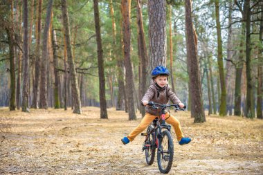 Güzel sonbahar gününde bir bisiklet ile sonbahar ormandaki eğleniyor 3 veya 5 yıllık mutlu bir çocukluk oğlan. Etkin alt giyen Bisiklet kask. Güvenlik, spor, eğlence çocuk kavramı ile