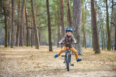 Güzel sonbahar gününde bir bisiklet ile sonbahar ormandaki eğleniyor 3 veya 5 yıllık mutlu bir çocukluk oğlan. Etkin alt giyen Bisiklet kask. Güvenlik, spor, eğlence çocuk kavramı ile