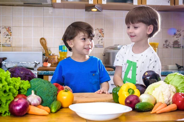 Healthy eating. Happy children prepares and eats vegetable salad in kitchen. Health and friendship concept.