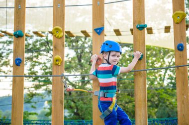 Çocuk Macera Parkı'nda eğleniyor. bir ip Bahçesi yapısında tırmanma yürümeye başlayan çocuk. bir ip Bahçesi yapısında tırmanma yürümeye başlayan çocuk. Kask ve kemer ile güvenli tırmanma aşırı spor