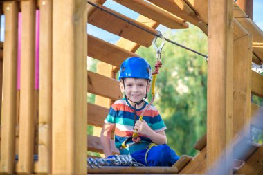 Küçük şirin çocuk aktivite bir tırmanma macera parkta yaz güneşli bir günde zevk. bir ip Bahçesi yapısında tırmanma yürümeye başlayan çocuk. Kask ve kemer ile güvenli tırmanma aşırı spor. sigorta